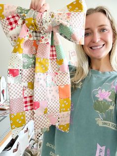 a woman holding up a large bow made out of quilts and fabric pieces in front of her face