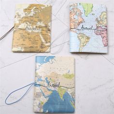 three notebooks with the words travel written on them and a world map behind them