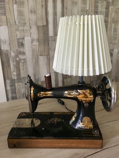 an old sewing machine sitting on top of a wooden table next to a white lamp