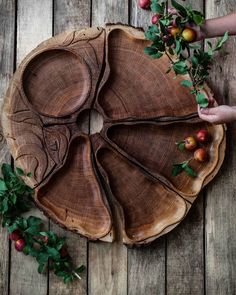 a wooden tray with apples on it and leaves in the center, sitting on a wood floor