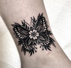 a black and white butterfly tattoo on the ankle