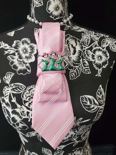 This Pink and White Stripe Necktie Necklace is made with a (Barry Wang) woven silk tie, and features a Sliver, Pink and Green Sisterhood Brooch strung on your choice of an adjustable Rosary Chain Ribbon Tie Pearl Necklace or an adjustable Elastic Band. The soft, comfortable fabric sits perfectly on any size chest, while the adjustable necklace feature allows you to customize the fit to your liking. Measuring at a versatile length, this necktie necklace is designed to be a one-size-fits-all. View Necktie Necklace, Graduation Outfit College, Women Necktie, Aka Sorority, Graduation Outfits, Tie Necklace, Women Ties, Handmade Beaded Necklaces, Rosary Chain