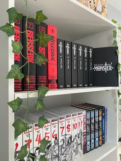 the books are lined up on the shelves in front of the plant and other items