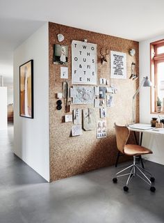 a room with a desk, chair and bulletin board on the wall next to it