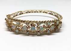 "Estate 14k Yellow Gold Filigree W/ Rope Edge Detail Opal & Diamond Hinged Bangle Bracelet Material: 14k yellow gold, stamped Weight: 22.9 grams Size: Top is 12mm wide tapering to 10.50mm on sides and 5mm on bottom, Bracelet is 2.50mm in diameter, 2 1/2\" attached safety chain Stones: 7 round fiery opals 3.70 - 4mm each 8 round fiery opals 2.50 - 2.60mm each 4 round cut diamonds 2.50 - 2.60mm each, SI2 - I1 clarity, G - H color Hallmarked: 14k Side hinge opening with a safety figure 8 Side h Ornate Gold Bracelets With Jewels, Heirloom Gold Bracelets With Jewels, Heirloom Style Gold Bracelets With Jewels, Yellow Gold Jeweled Round Bracelets, Yellow Gold Filigree Bracelets, Antique Yellow Gold Bracelet For Evening Wear, Antique Yellow Gold Bracelets For Evening, Elegant Round Gold Filigree Bracelet, Ornate Hallmarked Yellow Gold Bracelet