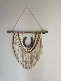 a wall hanging with beads and wooden beads on it's end, attached to a white wall