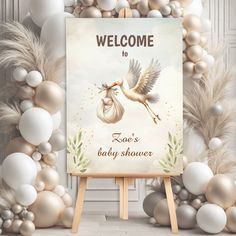 a welcome sign with a stork carrying a baby in its mouth and balloons around it