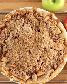 an apple pie on a table with apples around it