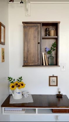 a wooden cabinet sitting on top of a table next to a vase filled with flowers