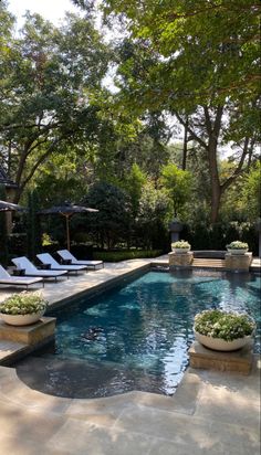 an outdoor swimming pool with lounge chairs and trees in the backgroung area