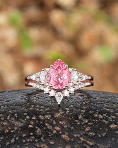 a pink diamond ring sitting on top of a rock