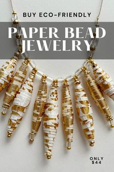 the paper bead jewelry is hanging from a necklace with gold and white beads on it