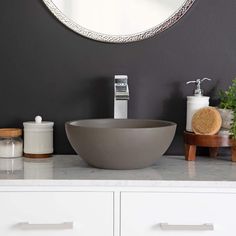 a bowl sink sitting on top of a white counter next to a mirror and soap dispenser