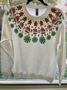 Reminiscent of the wildly popular puffy paint fashions in the 80's & 90's. Handmade fabric applique Christmas sweatshirt. Each motif is individually cut from 100% cotton fabric and collaged together to create a stunning arrangement. The finishing touches include multi-colored glitter puffy paint outlining each motif in addition to many rhinestones to add the perfect amount of sparkle.  Sizing: Adult unisex Gildan sweatshirt Cheap Vintage Christmas Sweater, Festive Holiday Cotton Sweater, White Christmas Tops With Embroidered Graphics, Fun White Sweatshirt For Winter, Holiday Cotton Sweater With Graphic Print, White Casual Sweater For Festive Occasions, Casual White Sweater For Festive Occasions, Casual White Festive Sweater, Holiday White Graphic Print Sweatshirt