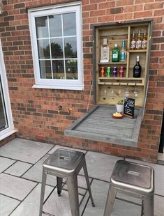 an outside area with two metal trash cans and a wooden shelf filled with liquor bottles