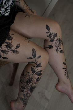 a woman's legs with tattoos on them sitting in front of a table and chair