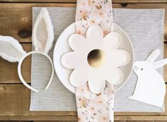 an easter table setting with bunny ears, napkins and paper flowers on the place mat