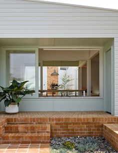 a house with brick steps leading up to the front door and back porch area that has a potted plant on it