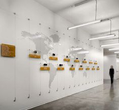 a man walking past a white wall covered in yellow and black magnets