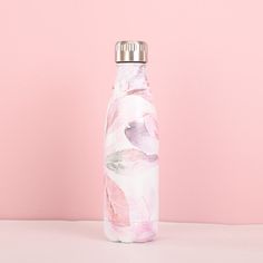 a pink and white floral water bottle with a silver lid on a light pink background