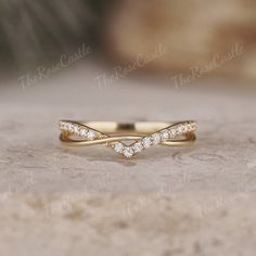 a gold wedding band with three diamonds on top, sitting on a stone surface in front of the camera