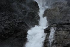 a large waterfall is coming down the side of a mountain