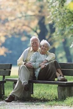 an older couple sitting on a park bench