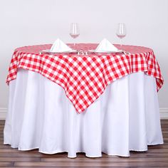 a red and white checkered table cloth with two wine glasses on top is shown