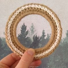 a hand holding a rope ring with trees in the background