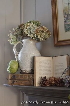 an open book sitting on top of a table next to a vase filled with flowers