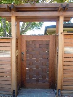 an open wooden gate in front of a tree