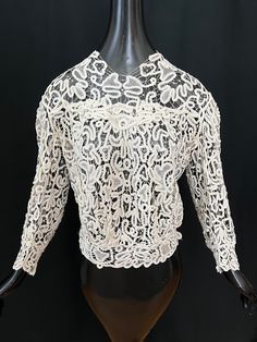 "Beautiful antique Victorian/Edwardian finely handmade intricate tape lace blouse in a warm antique white or light cream color. Very lovely with fine details to the lace with delicate needle lace fillings. It has a blouson fit with pigeon style in front with two gathers above the fitted waist, an overlapping lace design in the center of the bust and around the back, the sleeves are gathered at the shoulders, full and curved around the elbows graduating to a narrower fit at the cuffs with outer side of the sleeve being longer. It snaps closed down the back. The lace is a heavier weight with hand done stitches.  Condition: Good antique condition, clean freshly laundered, there is a light beige spot on the waistband, the connecting brides are quite fine and some have broken most have been lig Elegant Cotton Lace Top, Elegant Lace Crochet Top With Lace Trim, Elegant Crochet Top With Lace Trim, Elegant Cotton Lace Top With Lace Trim, Elegant Cotton Lace Top With Lace Work, Elegant White Crochet Top With Lace Sleeves, Vintage White Lace Crochet Top, White Vintage Lace Crochet Top, Elegant Cotton Lace Top With Lace Collar