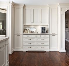 a kitchen with white cabinets and wood flooring, along with a coffee maker on the counter