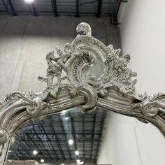 an ornate silver mirror is shown in the middle of a room with white walls and ceilings