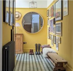 the hallway is painted bright yellow and has pictures on the wall, along with a bench