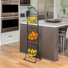 two baskets filled with fruit on top of a metal rack next to an island in a kitchen