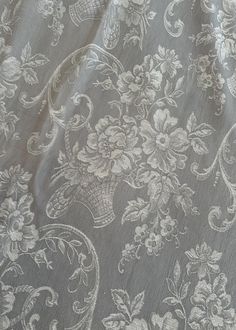 the fabric is made up with white flowers and leaves on grey background, as well as an intricate design