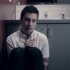 a man sitting on the floor in front of a kitchen sink