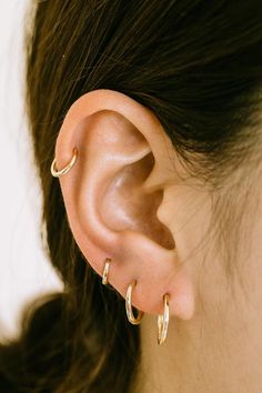 a close up of a woman's ear with gold hoops on the side