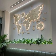 the world map is mounted on the wall above a bench in front of some plants