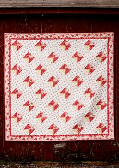 a red and white quilt hanging from the side of a barn