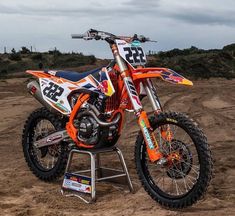 an orange dirt bike parked on top of a dirt field