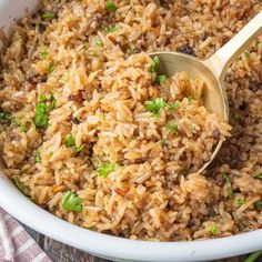 a white bowl filled with rice and topped with a wooden spoon next to a napkin