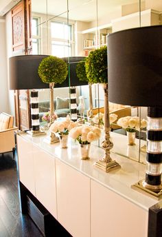 a white dresser topped with lots of vases filled with flowers next to a mirror