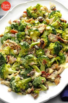 a white plate topped with broccoli covered in cheese and nuts next to a blue napkin