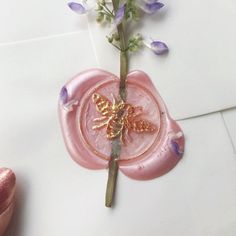 a pink flower with a butterfly on it sitting in front of a white tile wall