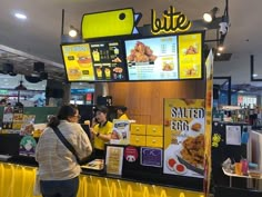 two people are ordering food at a fast food restaurant with yellow barriers around the counter