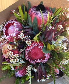 a bouquet of flowers sitting on top of a wooden table covered in leaves and berries