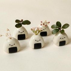 four small white vases with plants in them