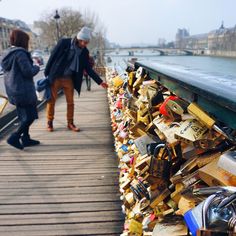 two people are walking on a bridge covered in locks